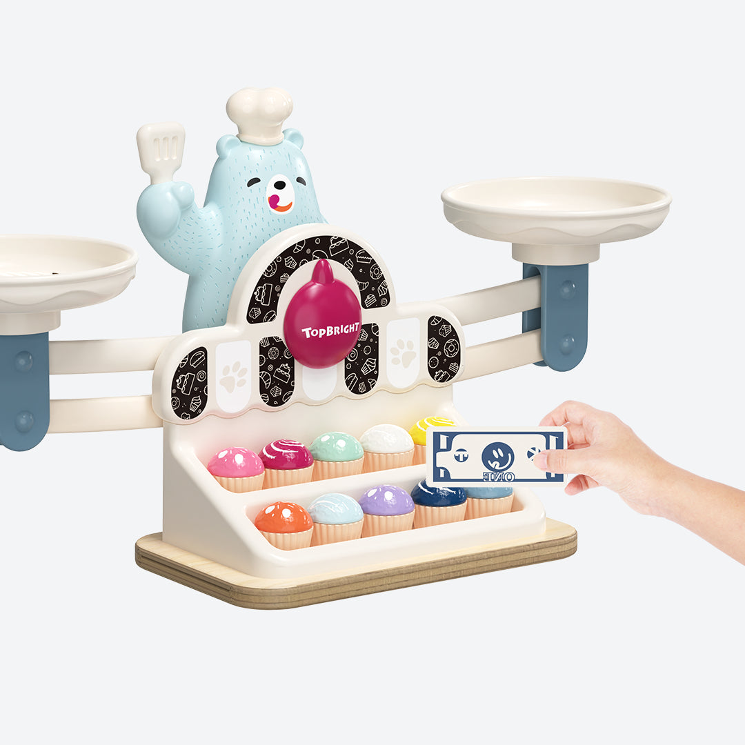 Close-up of Yummy Bear Scale in action, showing balance trays with numbered weights and cakes – playful introduction to weight and counting for preschoolers